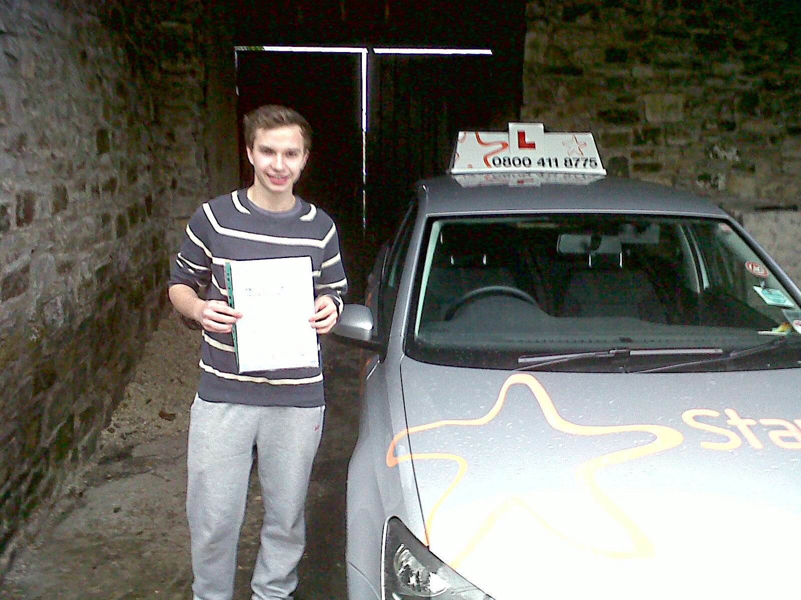 Jake with his Practical Driving Test Pass Certificate in Burtle sheltering from the rain!