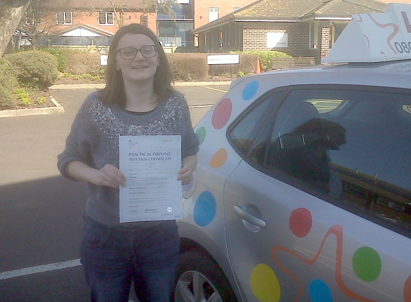 Emma with her Practical Driving Test Pass Certificate outside Weston-super-Mare Driving Test Centre.